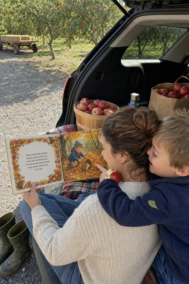 Dans le coffre de l'auto, au verger, un garçon lit en serrant sa maman